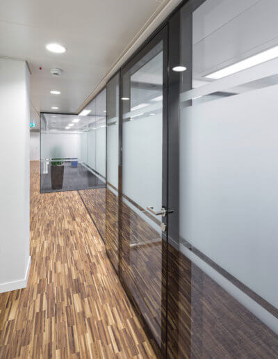 Der horizontale Sichtschutz auf den Glas Trennwänden harmoniert mit der Bodenstruktur.